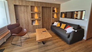 A modern living room with a wooden wall, a sofa, a coffee table, and a chair.