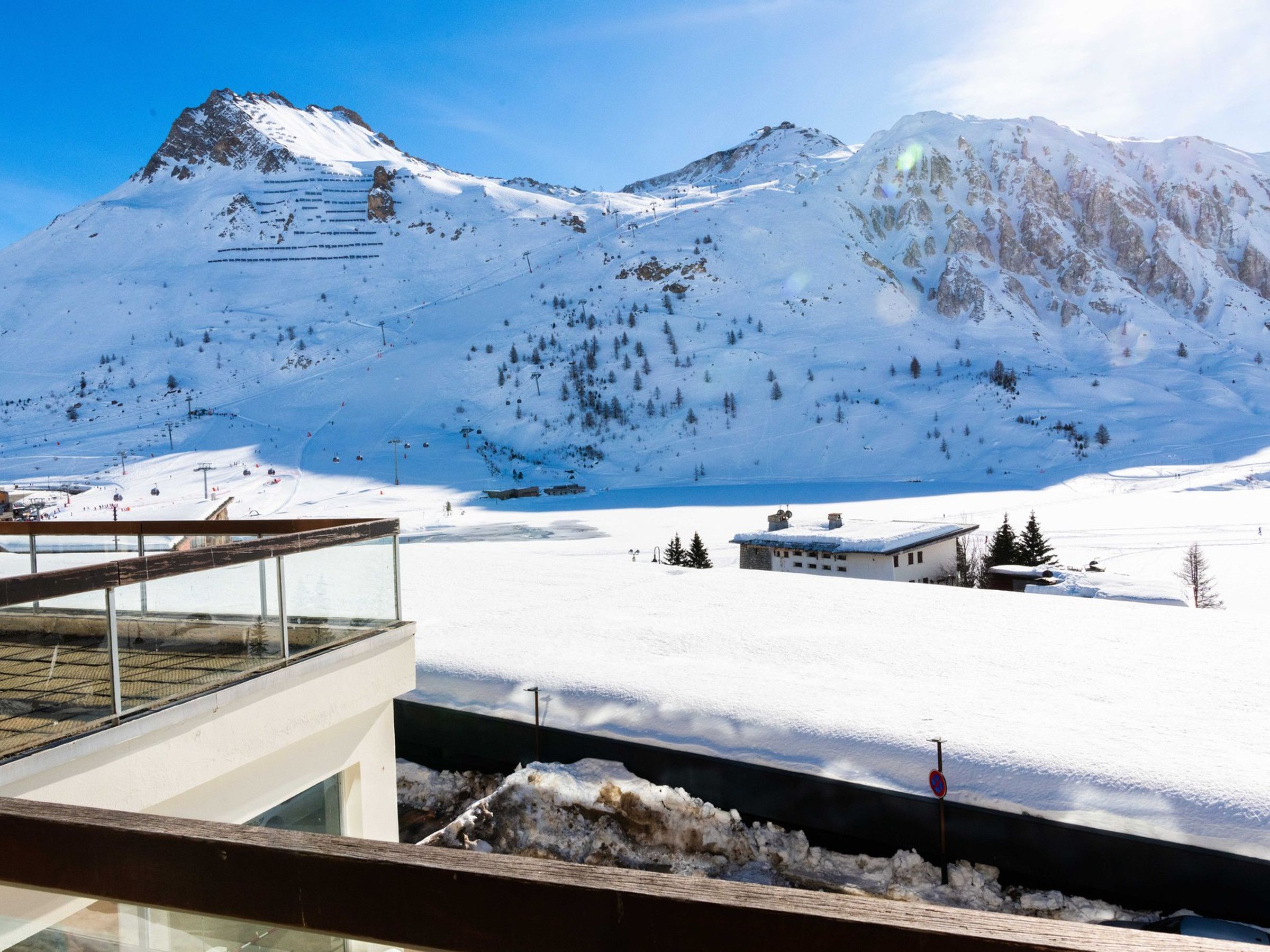 A snow-covered mountain landscape with a modern building featuring a glass balcony.
