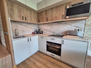 A modern kitchen with wooden cabinets, a built-in microwave, and a coffee maker.
