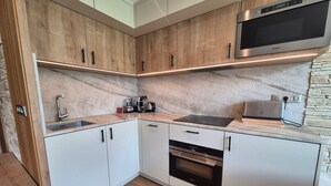 A modern kitchen with wooden cabinets, a built-in microwave, and a coffee maker.