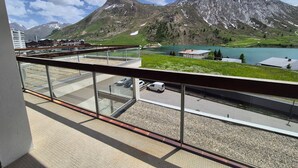 A balcony with a view of a mountain, a lake, and a parking area.