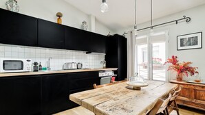 Una cocina moderna con armarios negros, una mesa de comedor de madera y vistas al exterior.