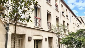 Un edificio con varios balcones, una bicicleta estacionada afuera y un árbol en primer plano.