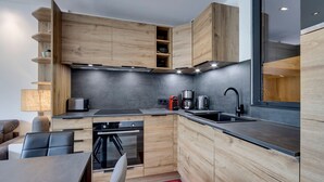 Una cocina moderna con armarios de madera, estufa integrada y un ventanal grande.