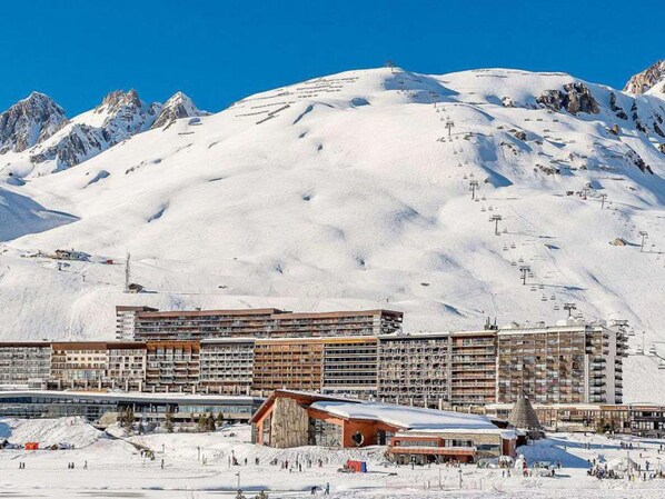 A hotel with multiple floors, ski slopes, and a mountainous backdrop.
