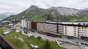 Un hotel de varios pisos, con estacionamiento y vistas a montañas al fondo.
