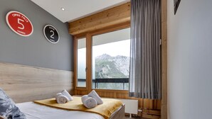 Un dormitorio con una cama, dos toallas, un ventanal con vista a la montaña y dos letreros en la pared.