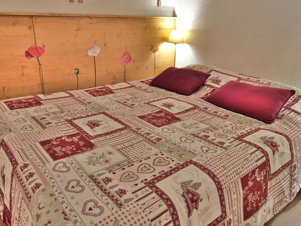 A bedroom with a wooden headboard, a patterned bedspread, and two pillows.