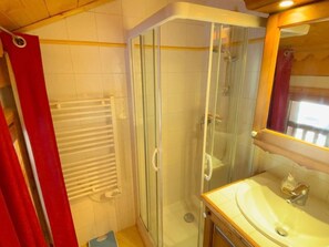 A bathroom with a glass-enclosed shower, a white towel rack, and a wooden vanity with a sink.