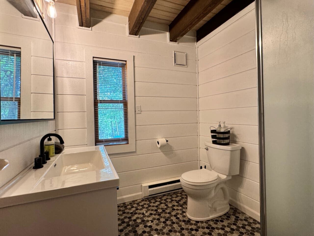A bathroom with a white sink, a toilet, and a window with blinds.