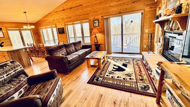 L’intérieur d’un chalet confortable, avec un plancher en bois, un canapé, une table basse et une cheminée.