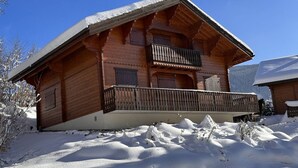 Una cabaña de madera con balcón, rodeada de nieve.