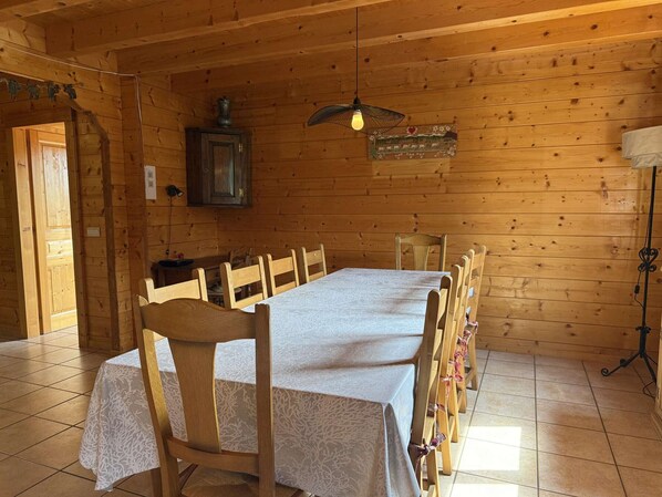 A wooden cabin interior with a long dining table, chairs, a hanging light fixture, and a cabinet. - Typical Chalet 5 Bedrooms for 10 People with Wi-Fi and Terrace (Les Carroz d'Arâches)