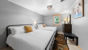 A bedroom with two beds, a window, a dresser, and a rug.