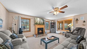 A cozy living room with a fireplace, large windows, and comfortable seating.