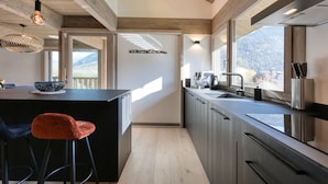 Una cucina moderna con una grande isola, sgabelli da bar e vista sulle montagne attraverso le finestre.
