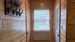 Un pasillo estrecho con paredes de madera y una ventana con persianas.