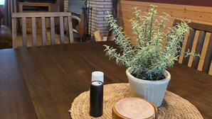 Una mesa de madera con un posavasos tejido, una planta en maceta y un candelabro.