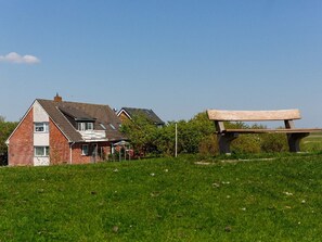 Una casa con techo inclinado, chimenea visible y césped.