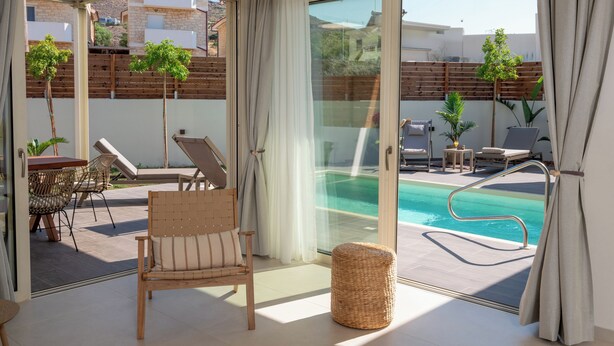 A spacious balcony with a pool, lounge chairs, and a wicker ottoman. - Alcyone - Gournes NewTown Residences (Heraklion)