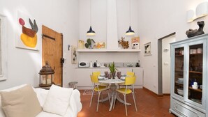 A compact living space with a dining area, kitchenette, and a cabinet with glass doors. - Oltrarno Art House - Florence (Firenze)
