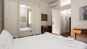 A hotel room with a large bed, a wardrobe, a desk, and a painting on the wall. - Oltrarno Art House - Florence (Firenze)