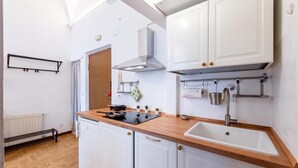 A modern kitchen with white cabinets, a wooden countertop, a built-in stove, and a sink. - Central Apartment Porta Soprana Genova (Genoa)