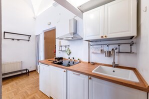 A modern kitchen with white cabinets, a wooden countertop, a built-in stove, and a sink. - Central Apartment Porta Soprana Genova (Genoa)