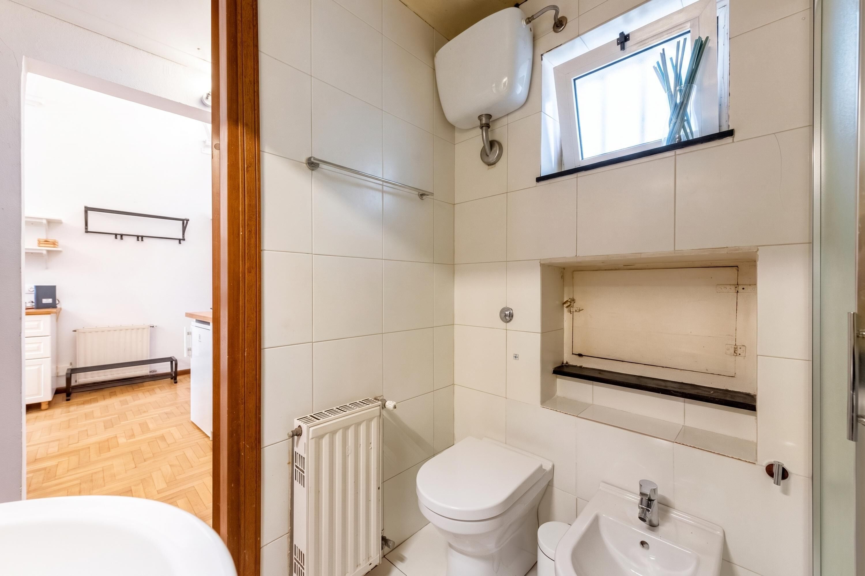 A modern bathroom with a toilet, sink, and window.