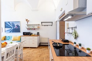 A compact kitchen with a dining area, white cabinetry, a microwave, and a black induction cooktop.