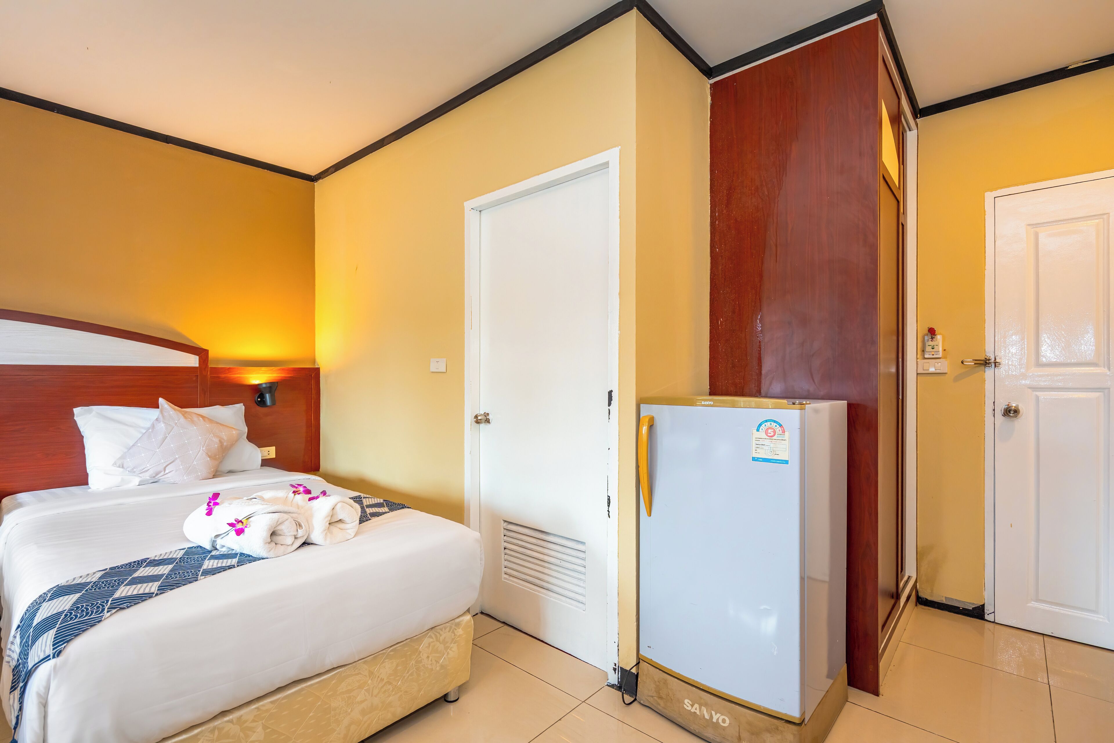 Habitació d'hotel amb un llit, un frigorífic blanc i un armari de fusta.