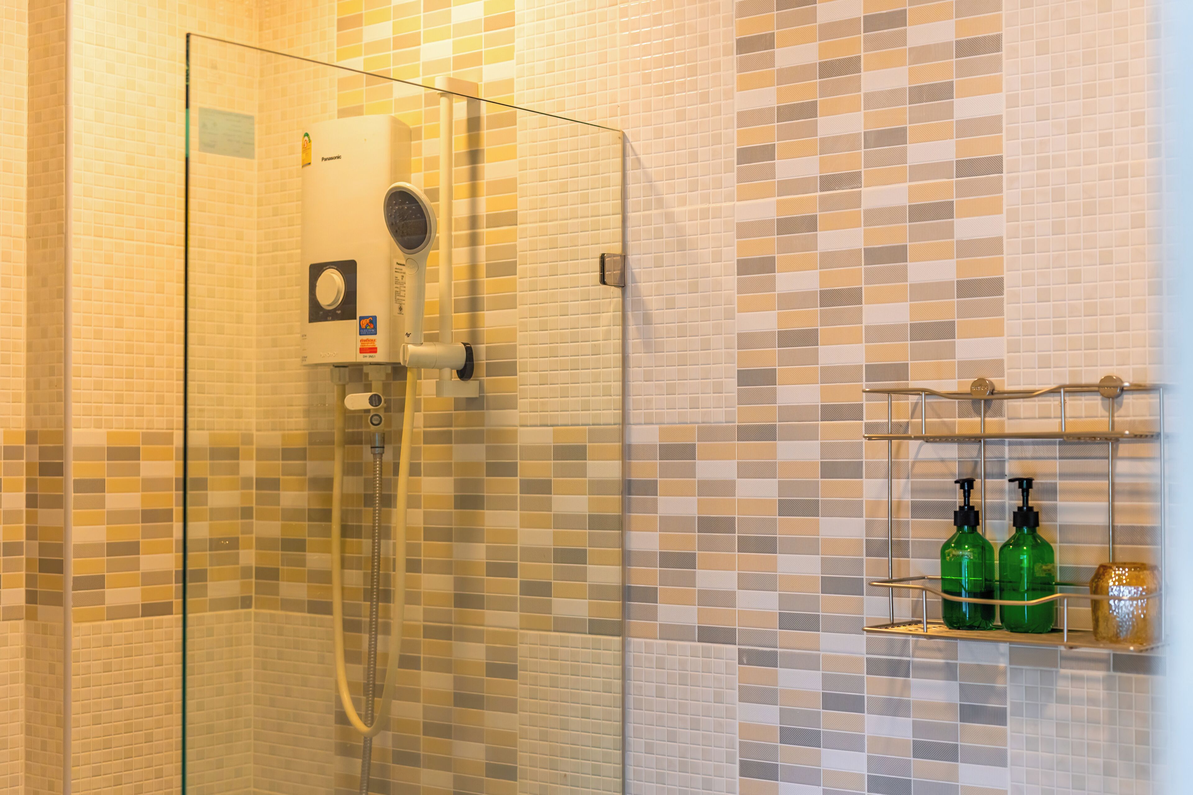 A glass-enclosed shower with a control panel and a tiled wall with a checkered pattern.