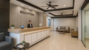A reception area with a receptionist, a reception desk, a sofa, and a coffee table. - The Outdoor Kata (Karon)