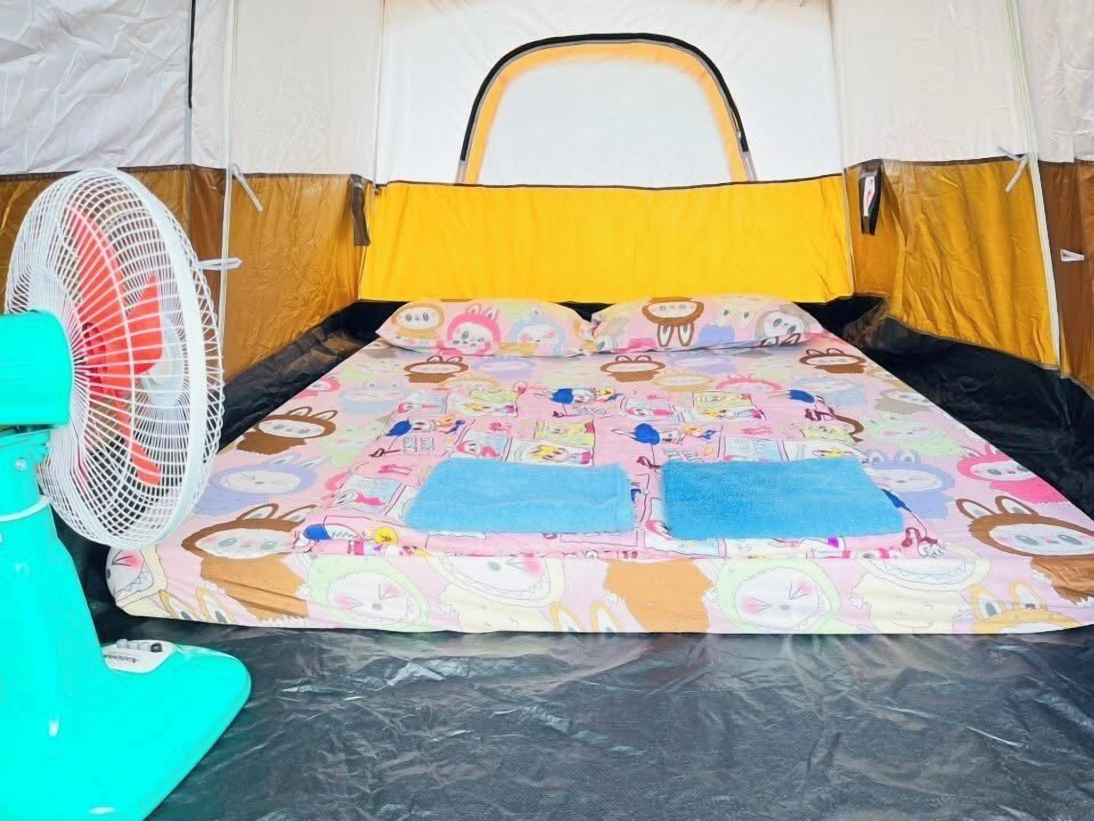 A tent with a colorful interior, a fan, and a teal chair.