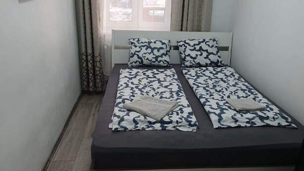A double bed with a patterned bedspread, a headboard, and a window with curtains. - Chic and Comfortable 1-Bedroom Stay in Vienna (Vienna)