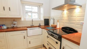 Una cocina con armarios blancos, estufa de acero inoxidable y una ventana sobre el fregadero.