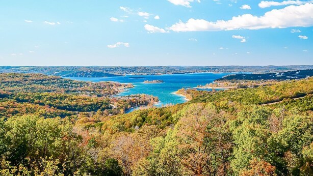 A panoramic view of a coastal landscape with a large body of water, surrounded by dense forests and hills. - Tree Top Terrace~NEW LISTING!~Pointe Royale Resort~Pools~Hottub (Branson)