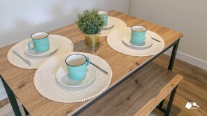 Une table en bois sur laquelle sont posées quatre tasses et soucoupes turquoise, chacune accompagnée d’une cuillère, et une petite plante en pot au centre.