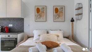 Une chambre d’hôtel moderne équipée d’un lit, d’une kitchenette et d’œuvres d’art accrochées au mur.