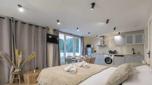 Une chambre d’hôtel moderne dotée d’un grand lit, d’une petite kitchenette, d’un coin repas et offrant une vue sur l’extérieur.