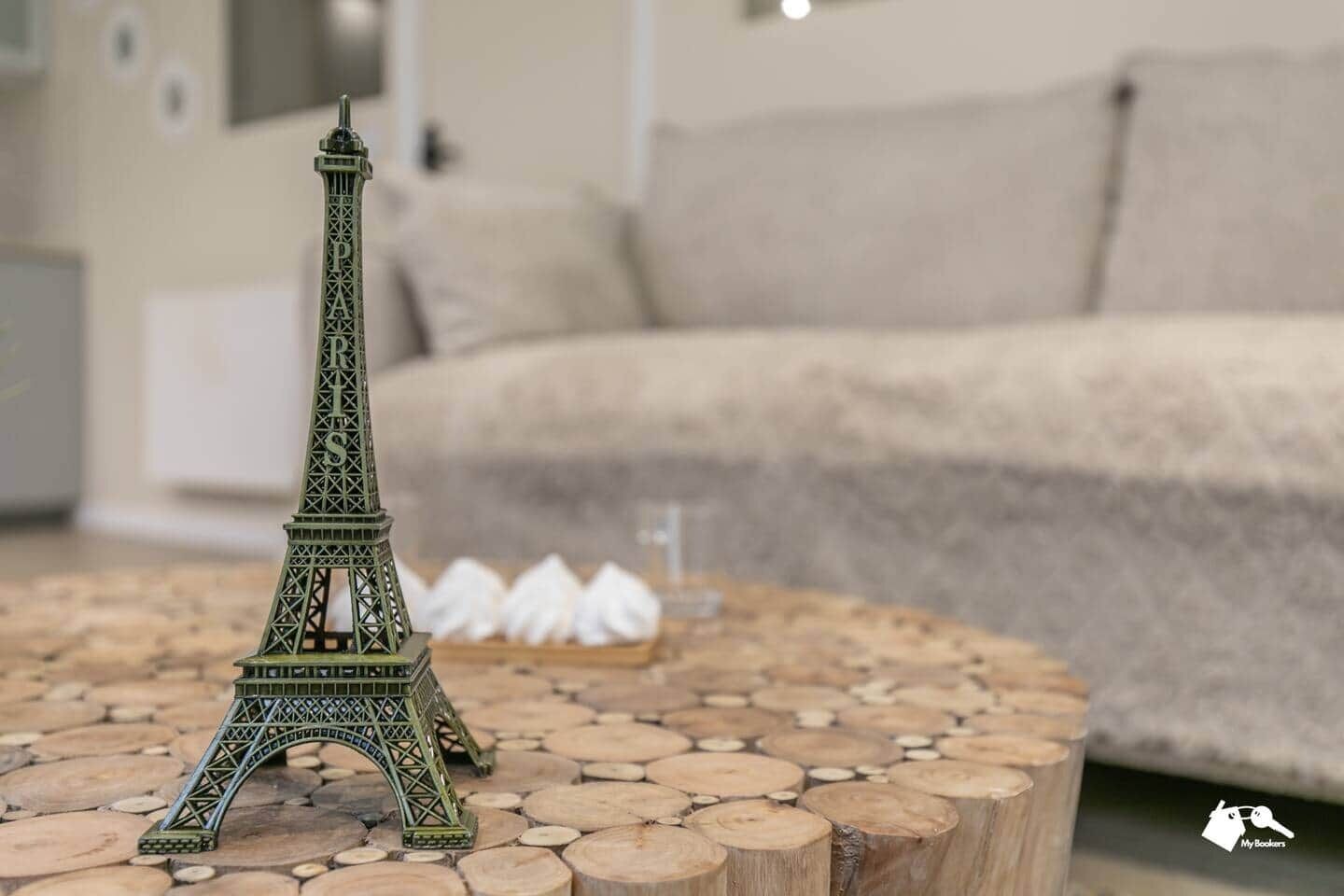 A model of the Eiffel Tower on a wooden coffee table in a living room with a sofa and cushions.