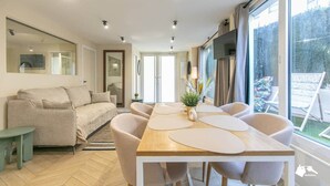 Un salon moderne avec un canapé, une table à manger et des chaises, un téléviseur et de grandes fenêtres.
