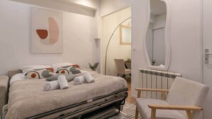 Un dormitorio moderno con una cama, una silla, un radiador y un espejo.