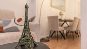 Una maqueta de la Torre Eiffel sobre una mesa en una habitación con comedor y una cama al fondo.