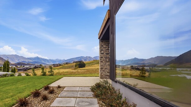 A modern building with a stone column, a concrete pathway, and a view of mountains and a lake. - Kirimoko Heights (Wānaka)