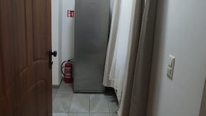 A narrow hallway with a closed door, a fire extinguisher, and a curtain. - Lovely Room 15 min to Center via U3 Enkplatz Metro (Vienna)