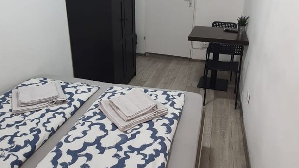 A small room with two beds, a desk, and a chair. - Lovely Room 15 min to Center via U3 Enkplatz Metro (Vienna)