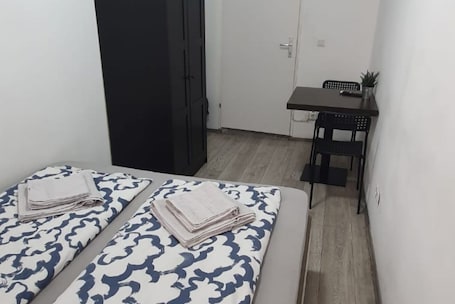 A small room with two beds, a desk, and a chair.