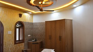 Une chambre avec une armoire en bois, un ventilateur de plafond et une petite table de chevet avec une lampe.