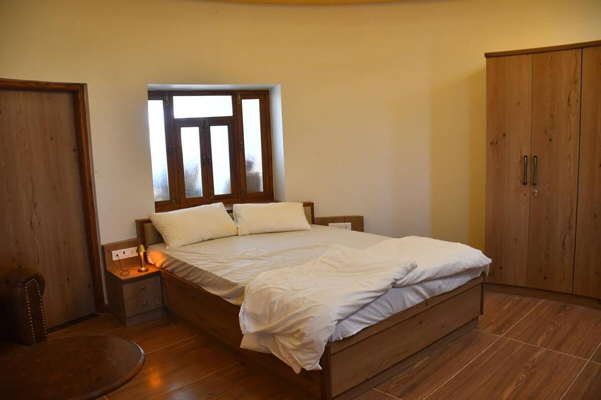 Ein Schlafzimmer mit einem hölzernen Bett, einem Nachttisch, einem Fenster und einem Kleiderschrank.